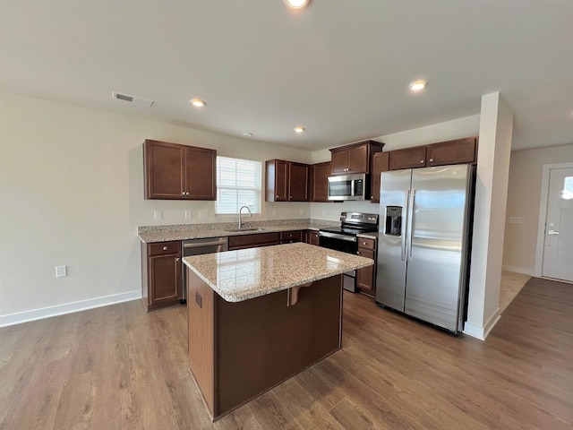 kitchen featuring wood finished floors, visible vents, a sink, appliances with stainless steel finishes, and a center island