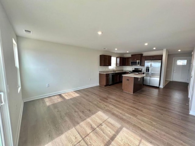 kitchen with visible vents, wood finished floors, open floor plan, a center island, and stainless steel appliances