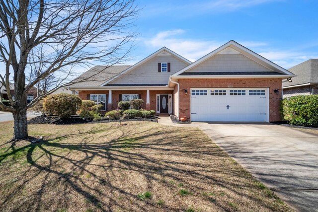 craftsman-style home featuring brick siding, driveway, a front lawn, and a garage