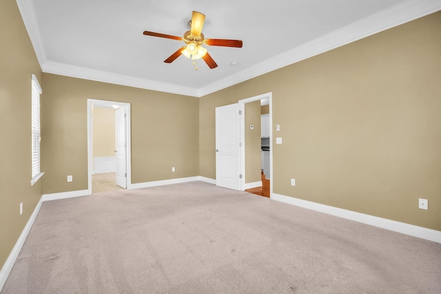 carpeted empty room with baseboards, a ceiling fan, and crown molding