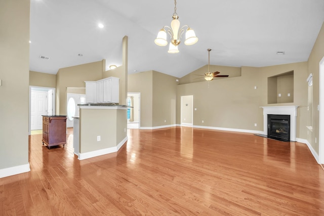 unfurnished living room featuring visible vents, baseboards, a glass covered fireplace, ceiling fan with notable chandelier, and light wood-type flooring