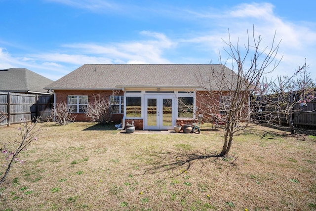 rear view of house featuring brick siding, french doors, fence private yard, and a yard