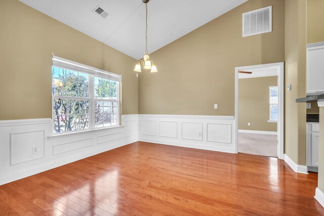 spare room with a notable chandelier, plenty of natural light, visible vents, and lofted ceiling