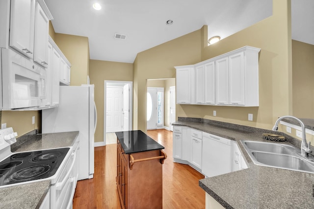 kitchen featuring visible vents, light wood-type flooring, a sink, a kitchen island, and white appliances