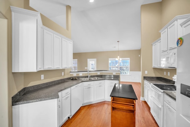 kitchen featuring a sink, white appliances, a peninsula, white cabinets, and light wood finished floors