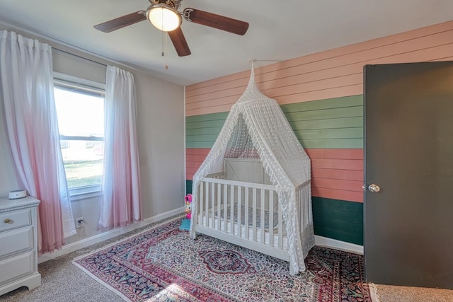 bedroom featuring baseboards, wooden walls, and a ceiling fan