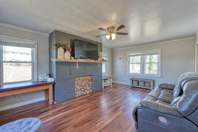 living area featuring crown molding, baseboards, ceiling fan, a fireplace, and wood finished floors