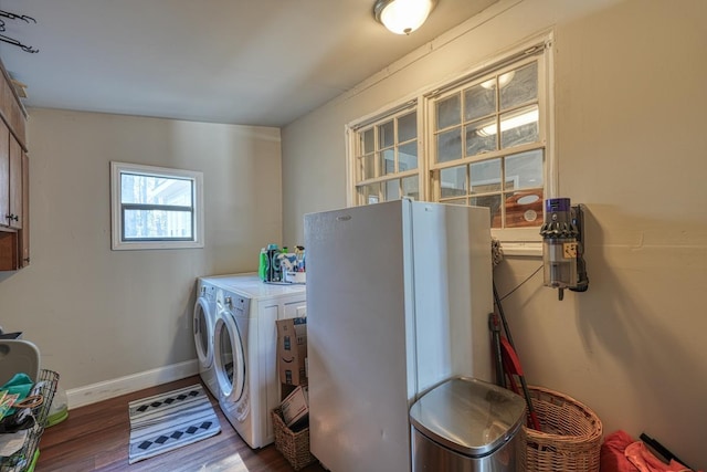 washroom featuring cabinet space, independent washer and dryer, baseboards, and wood finished floors