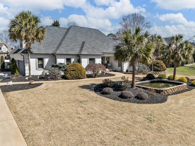 view of front of house with a front lawn and a shingled roof