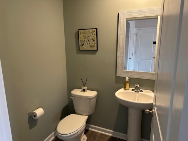 bathroom with toilet, baseboards, and wood finished floors