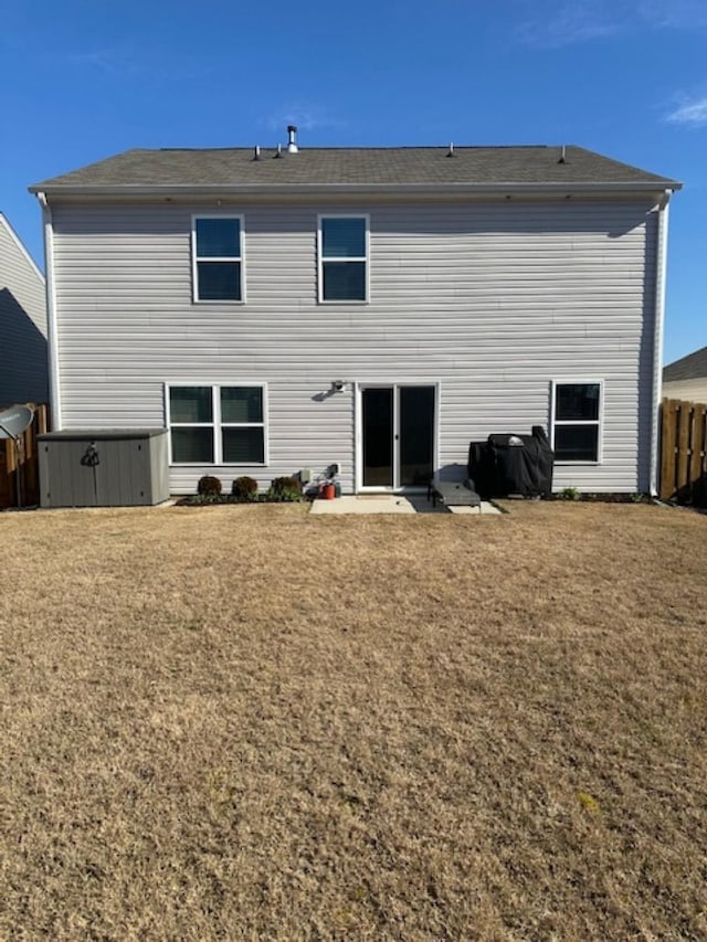 rear view of house with a lawn and fence