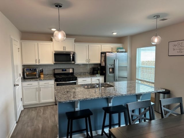 kitchen featuring backsplash, appliances with stainless steel finishes, dark wood-style floors, white cabinetry, and a sink