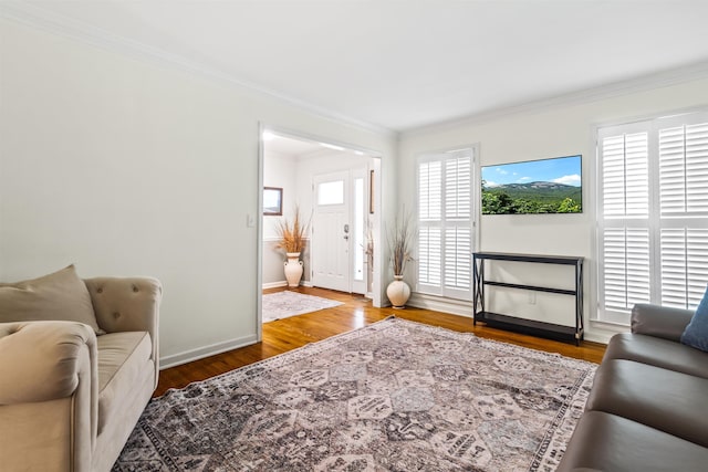 living area featuring crown molding, wood finished floors, and baseboards