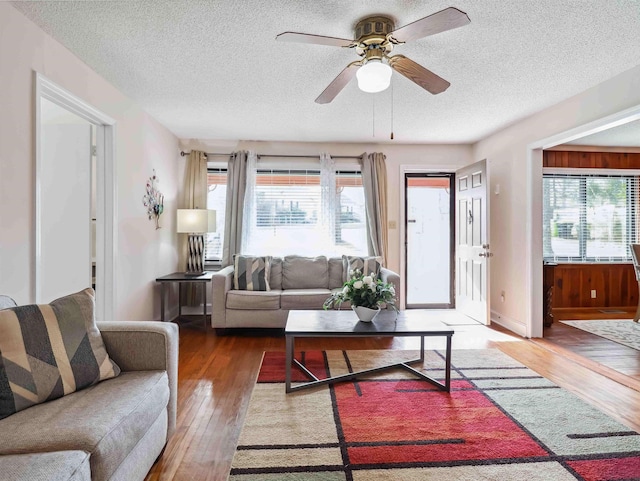 living area with a textured ceiling, hardwood / wood-style flooring, plenty of natural light, and ceiling fan