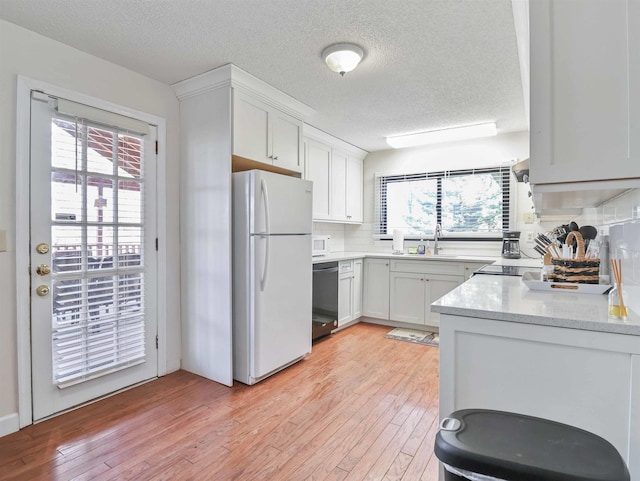 kitchen with backsplash, dishwasher, light wood-type flooring, and freestanding refrigerator