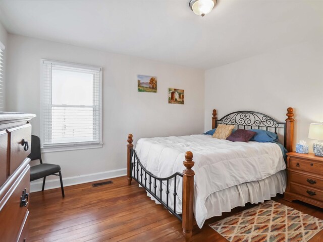 bedroom with hardwood / wood-style floors, baseboards, and visible vents