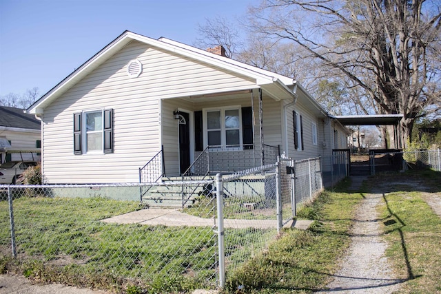 view of front of house featuring a fenced front yard, driveway, an attached carport, and a front lawn