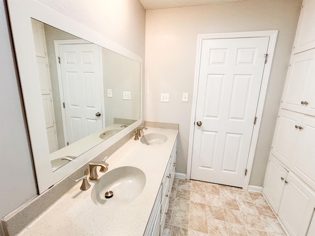 bathroom with a sink, baseboards, and double vanity