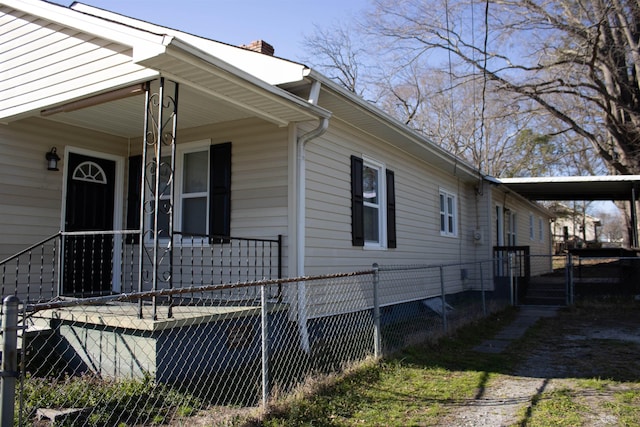 view of side of property featuring a carport, a porch, a chimney, and fence