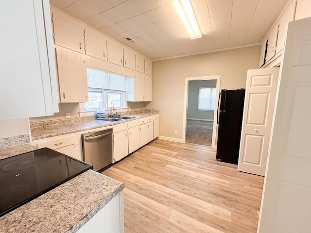 kitchen with stainless steel dishwasher, light countertops, freestanding refrigerator, and a sink