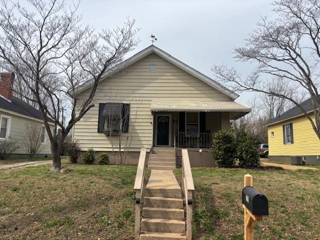 bungalow-style home featuring covered porch and a front lawn