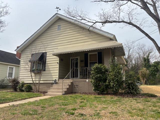 bungalow-style home with a front yard and covered porch