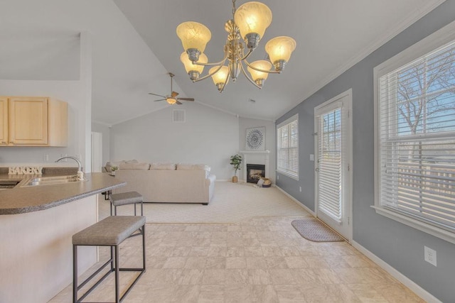 living area with ceiling fan with notable chandelier, vaulted ceiling, a fireplace, and baseboards