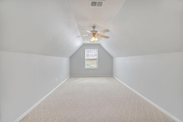 additional living space featuring carpet, baseboards, visible vents, ceiling fan, and vaulted ceiling