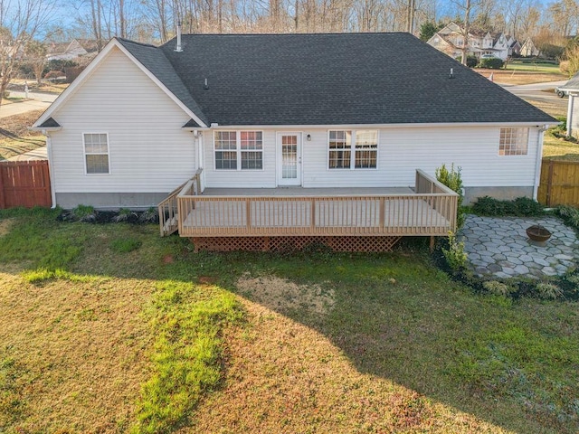 back of house featuring a wooden deck, a lawn, roof with shingles, and fence