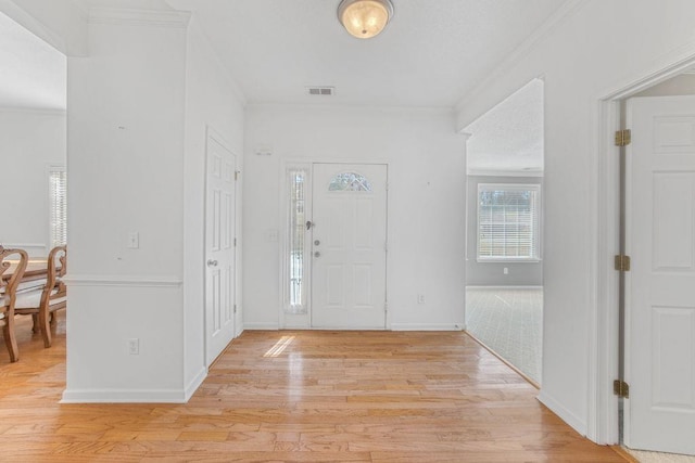 entryway featuring crown molding, light wood-style flooring, baseboards, and visible vents