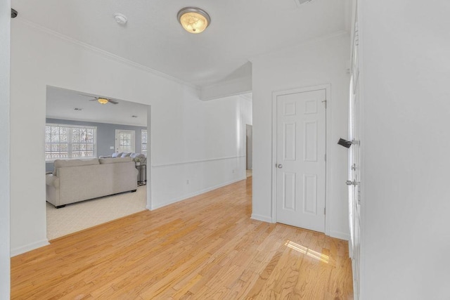 spare room featuring light wood-style flooring, baseboards, and ornamental molding