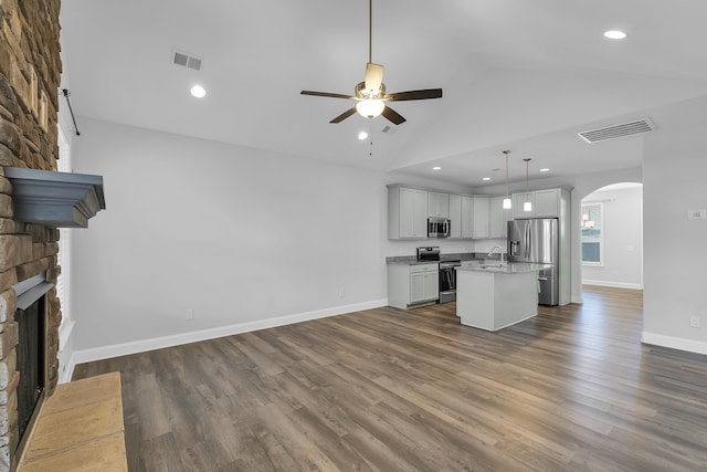 unfurnished living room with visible vents, a sink, a large fireplace, arched walkways, and ceiling fan