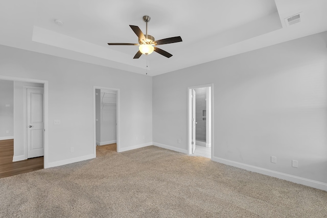 interior space featuring a ceiling fan, a tray ceiling, baseboards, and visible vents