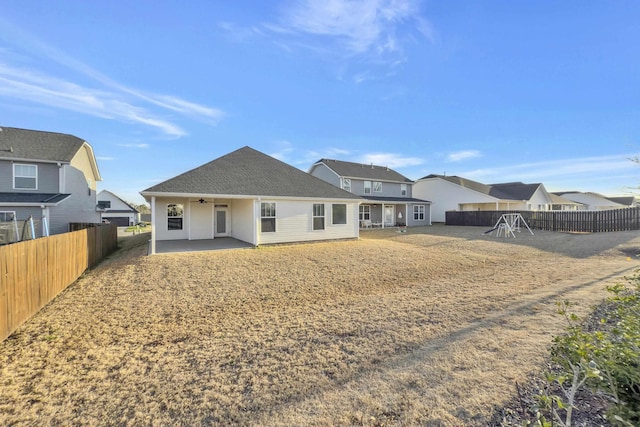 rear view of property featuring roof with shingles, a fenced backyard, a ceiling fan, and a patio area