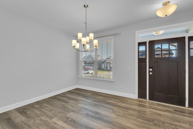 entryway with an inviting chandelier, baseboards, and dark wood-style flooring