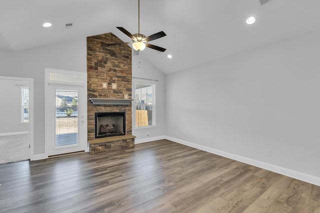 unfurnished living room featuring a stone fireplace, plenty of natural light, high vaulted ceiling, and dark wood-style flooring