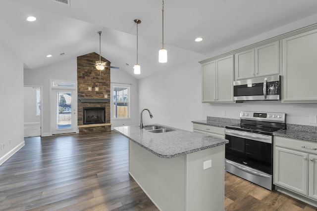 kitchen featuring light stone countertops, a fireplace, a sink, stainless steel appliances, and open floor plan