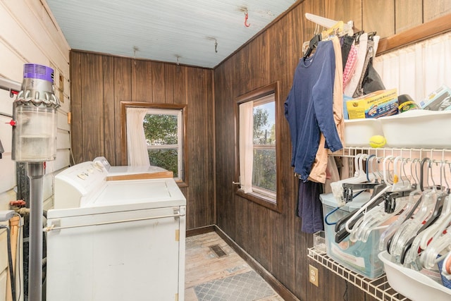 clothes washing area featuring washer and dryer, laundry area, visible vents, and wood walls