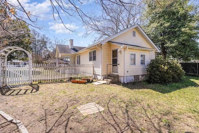 exterior space with entry steps, a front lawn, fence, and a chimney