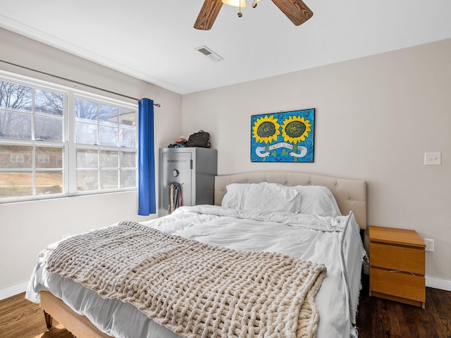 bedroom featuring ceiling fan, visible vents, baseboards, and wood finished floors