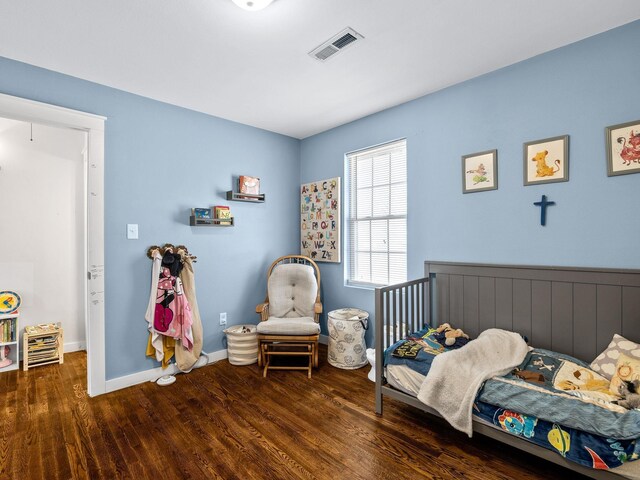 bedroom featuring visible vents, baseboards, and wood finished floors