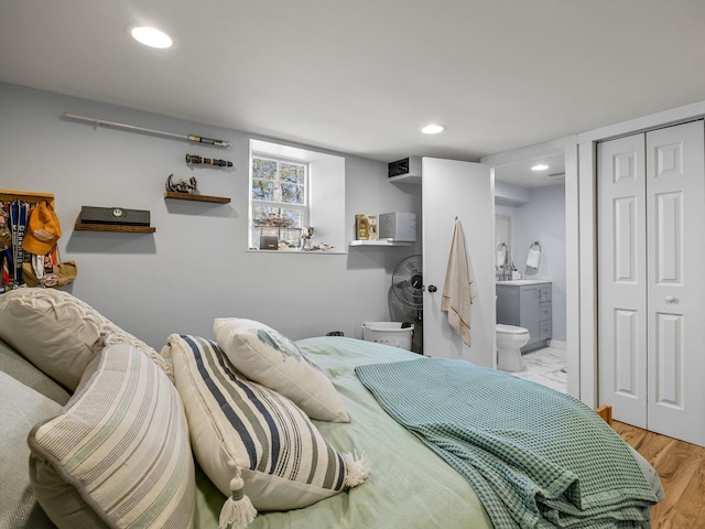 bedroom featuring a closet, recessed lighting, ensuite bath, and wood finished floors