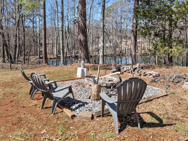 view of yard with a forest view, a water view, and an outdoor fire pit