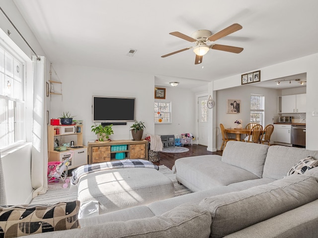 living room featuring visible vents, baseboards, wood finished floors, and a ceiling fan