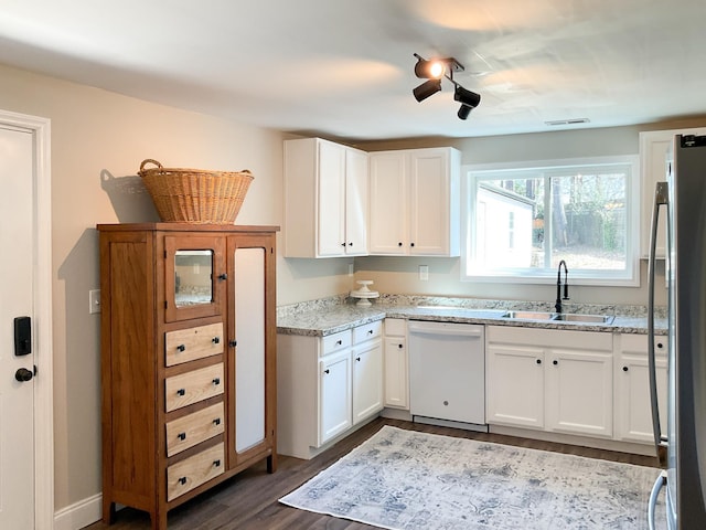 kitchen featuring visible vents, freestanding refrigerator, white dishwasher, white cabinets, and a sink