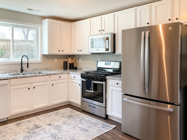 kitchen featuring visible vents, a sink, white cabinetry, appliances with stainless steel finishes, and dark wood-style flooring