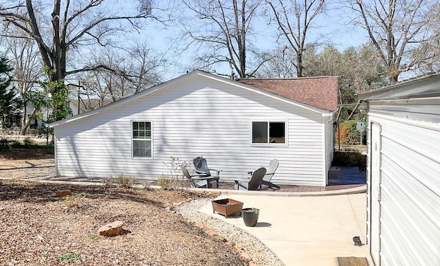 view of side of home with a patio and a shingled roof