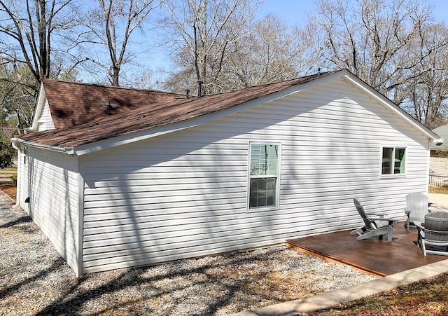 view of home's exterior with a shingled roof and a wooden deck