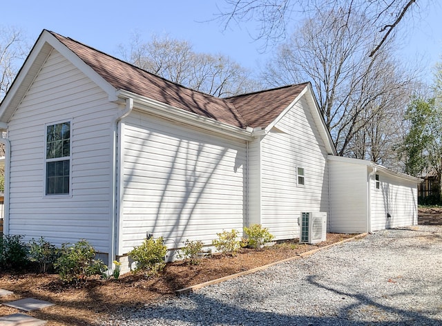 view of property exterior with a shingled roof and central AC