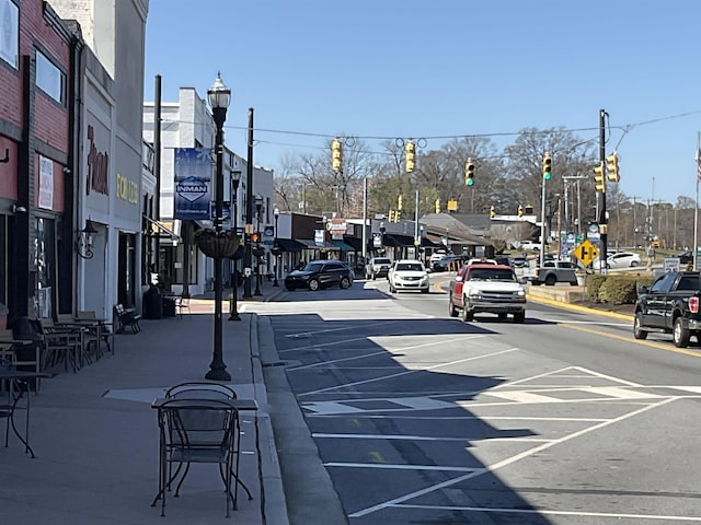 view of road featuring curbs, traffic signs, traffic lights, street lights, and sidewalks